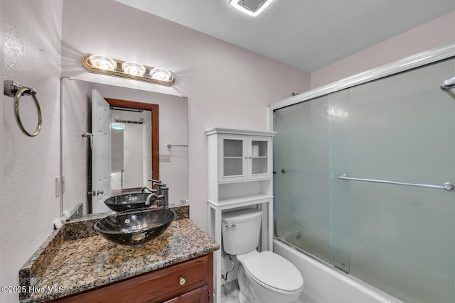 full bathroom with vanity, combined bath / shower with glass door, and toilet