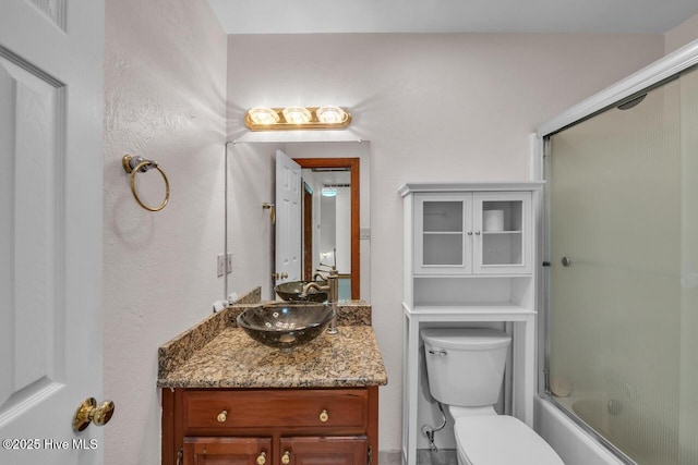 full bath featuring toilet, combined bath / shower with glass door, and vanity
