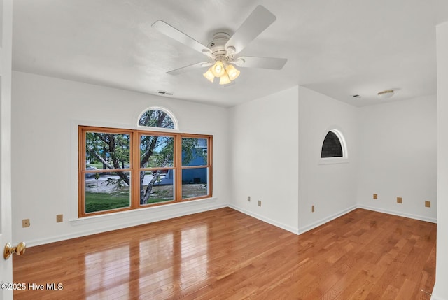 spare room with baseboards, a ceiling fan, wood finished floors, and visible vents