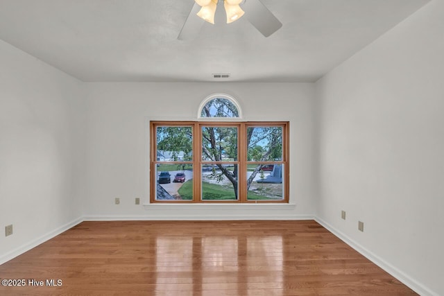 spare room with baseboards, ceiling fan, visible vents, and wood finished floors