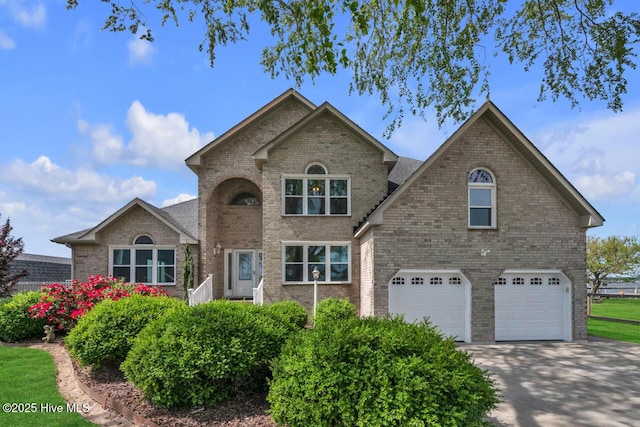 traditional-style house featuring brick siding, an attached garage, and driveway