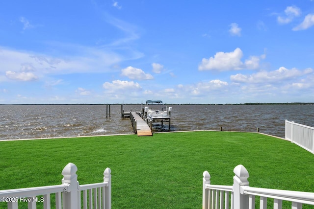 view of dock with a lawn and a water view