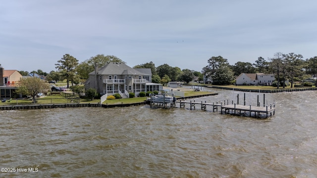 view of dock with a water view, a yard, and a balcony