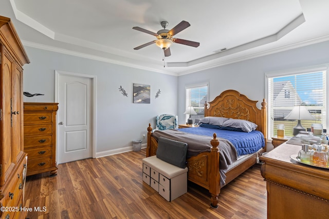 bedroom featuring a raised ceiling, dark wood-type flooring, baseboards, a ceiling fan, and crown molding