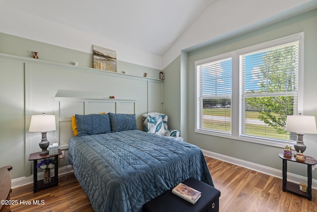 bedroom with vaulted ceiling, wood finished floors, and baseboards