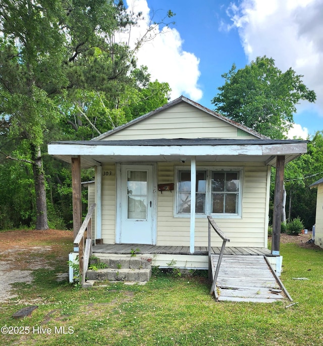 bungalow featuring covered porch and a front yard