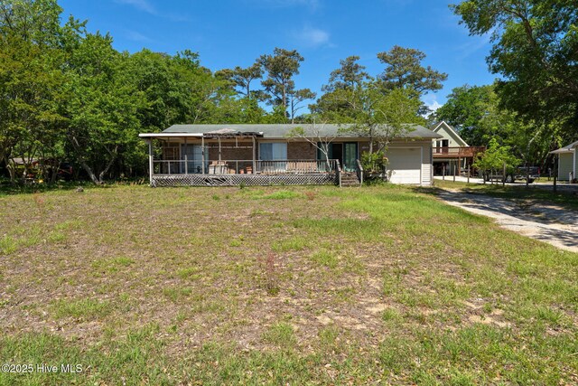 single story home with a front yard, an attached garage, driveway, and a sunroom