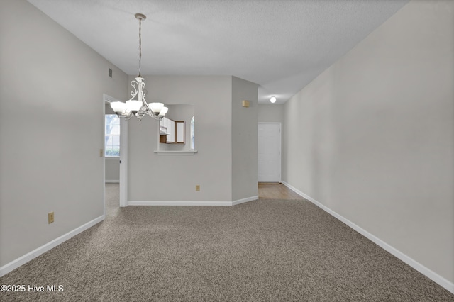 unfurnished room with a chandelier, carpet floors, baseboards, and a textured ceiling