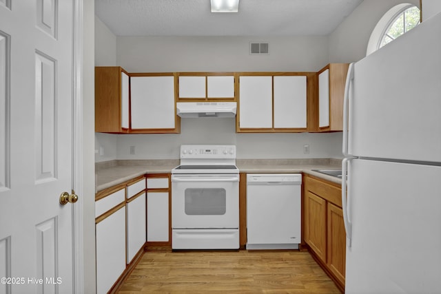 kitchen featuring white appliances, under cabinet range hood, light wood-style flooring, light countertops, and a textured ceiling
