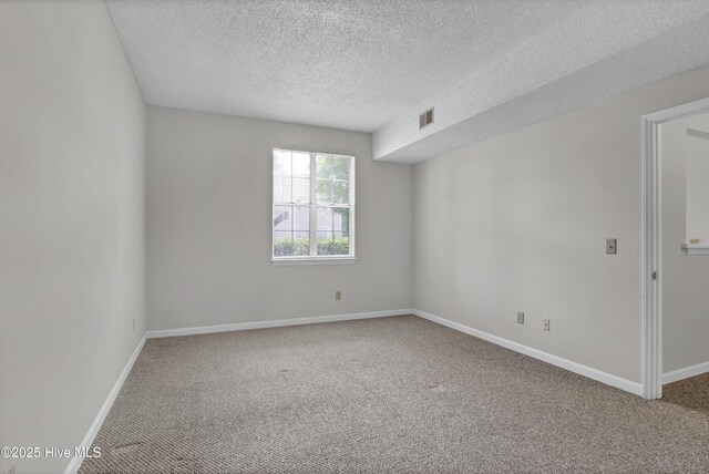 carpeted empty room with a textured ceiling and baseboards