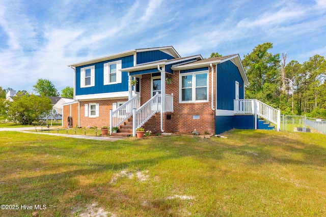 tri-level home featuring fence, a front yard, and brick siding