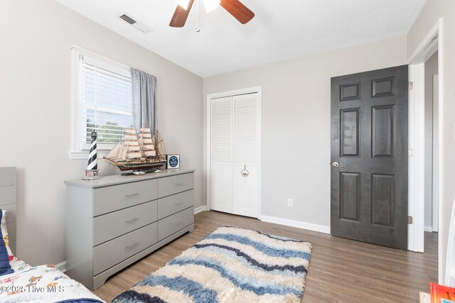 bedroom with visible vents, baseboards, wood finished floors, and a closet