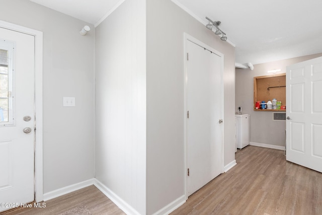 hall with washer / clothes dryer, baseboards, crown molding, and light wood finished floors