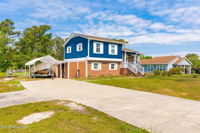 tri-level home with a detached carport, driveway, a front lawn, and brick siding