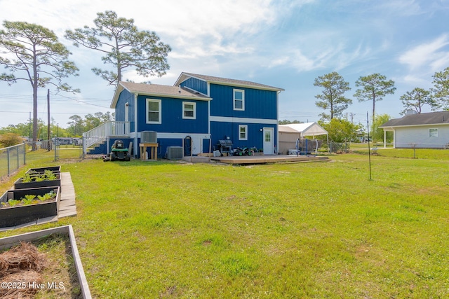 rear view of house with a lawn, a garden, fence, and a wooden deck