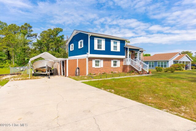 tri-level home with brick siding, a detached carport, driveway, and a front yard