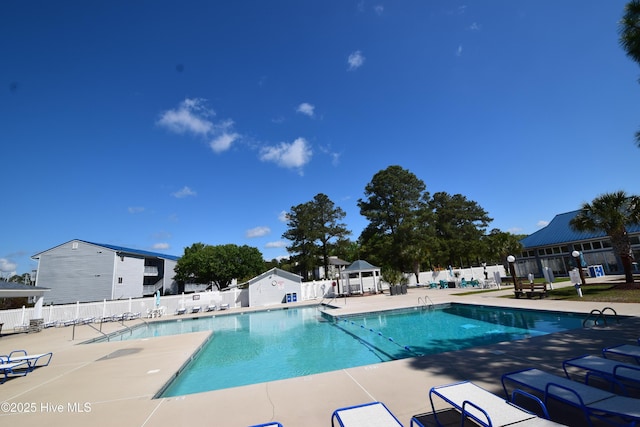 community pool with a gazebo, fence, and a patio