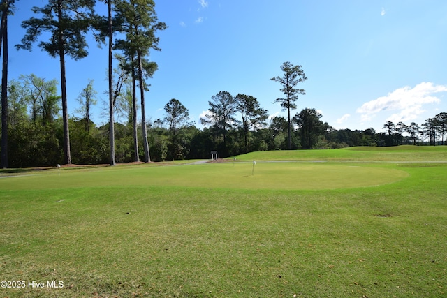 view of property's community featuring golf course view, a putting area, view of wooded area, and a yard