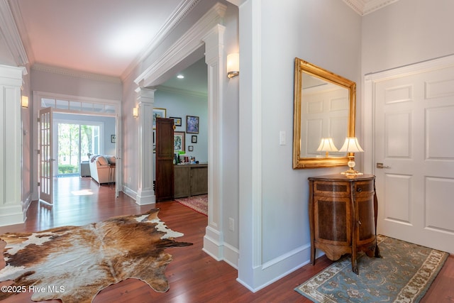 hallway featuring baseboards, ornamental molding, decorative columns, and wood finished floors
