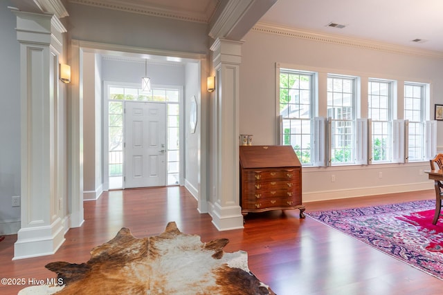 entrance foyer featuring crown molding, baseboards, wood finished floors, ornate columns, and visible vents