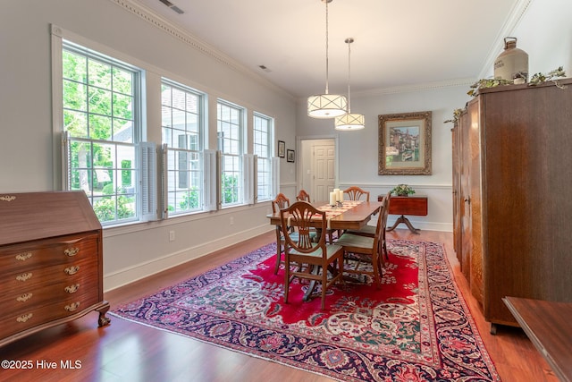 dining area featuring crown molding, baseboards, and wood finished floors