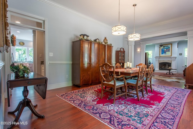 dining room with ceiling fan, wood finished floors, baseboards, a glass covered fireplace, and ornamental molding
