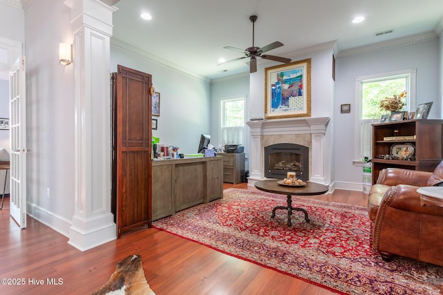 living area featuring crown molding, ceiling fan, a premium fireplace, wood finished floors, and visible vents