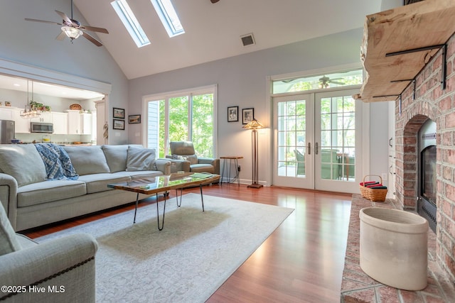 living area featuring ceiling fan, visible vents, high vaulted ceiling, and light wood-style floors
