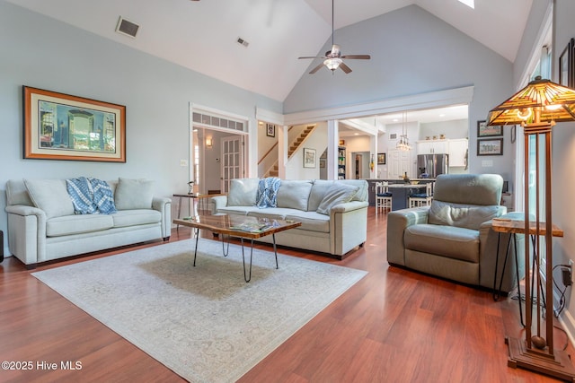 living room featuring ceiling fan, high vaulted ceiling, dark wood finished floors, stairs, and visible vents