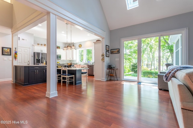 living area with high vaulted ceiling, a notable chandelier, dark wood-style flooring, and visible vents