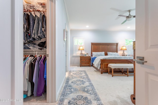 carpeted bedroom with a closet, ornamental molding, and a walk in closet