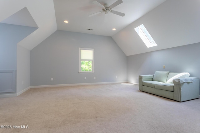 living area featuring light colored carpet, ceiling fan, vaulted ceiling with skylight, and visible vents