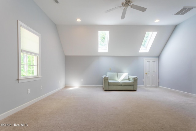 unfurnished room with a ceiling fan, visible vents, baseboards, lofted ceiling with skylight, and carpet