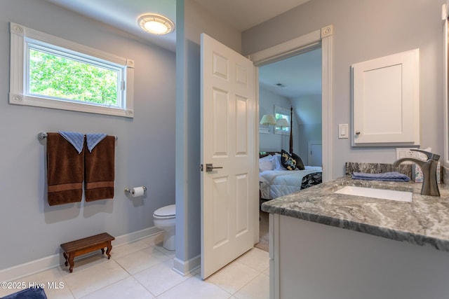 ensuite bathroom with vanity, tile patterned floors, baseboards, toilet, and ensuite bath