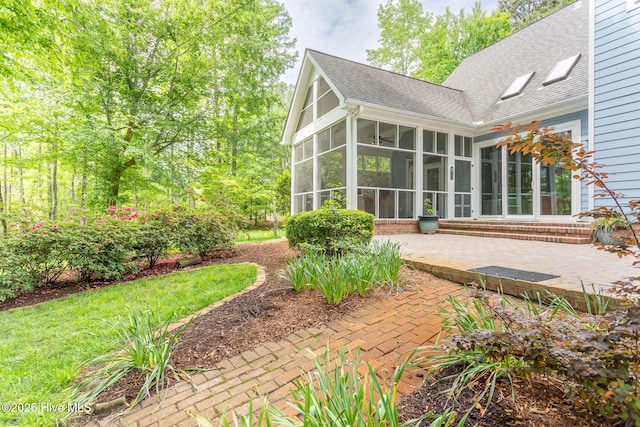 rear view of house with a patio, a shingled roof, and a sunroom