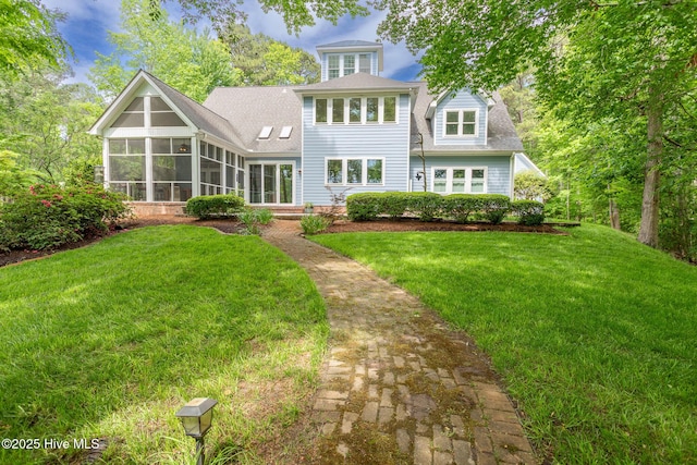 back of house featuring a lawn, roof with shingles, and a sunroom
