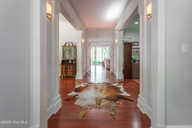 hall with crown molding, decorative columns, and wood finished floors