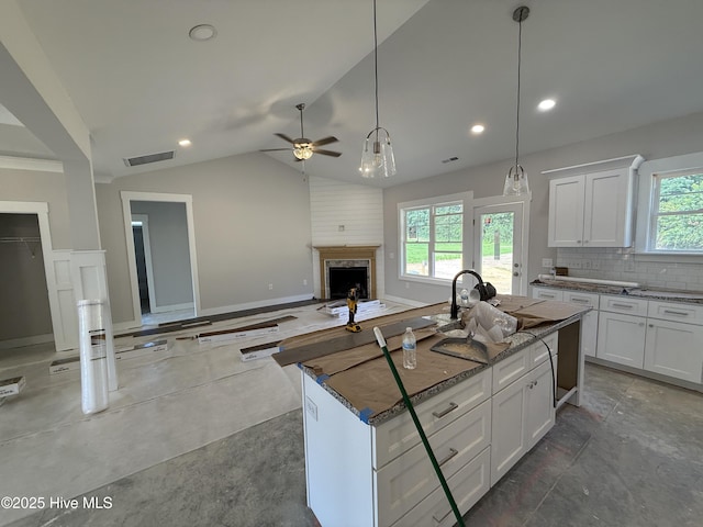 107 Tee Dr, Selma, NC 27576 - kitchen with white cabinets, stone countertops, a fireplace, ceiling fan, and a center island with sink