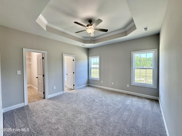 unfurnished bedroom with crown molding, a tray ceiling, and carpet