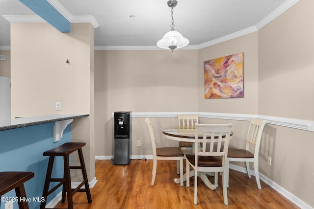 dining space featuring baseboards, ornamental molding, a textured ceiling, and wood finished floors