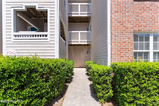 property entrance with a balcony and brick siding