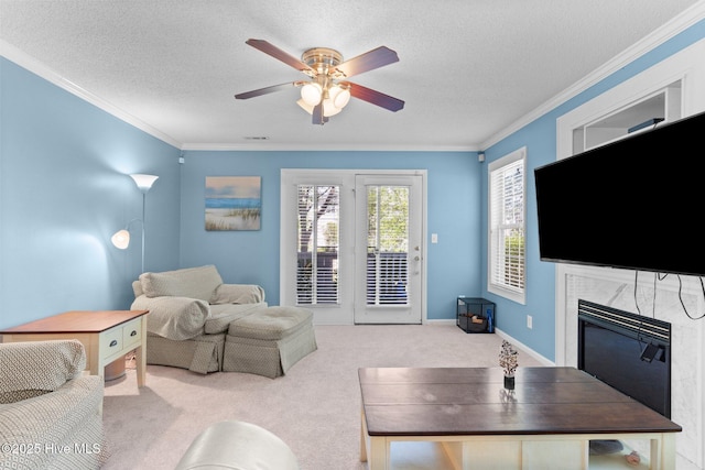 carpeted living room featuring a ceiling fan, a textured ceiling, ornamental molding, and a fireplace
