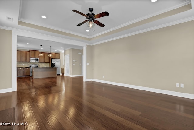 unfurnished living room with ceiling fan, baseboards, a tray ceiling, visible vents, and dark wood-style floors