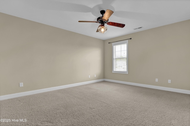 carpeted spare room with baseboards, ceiling fan, and visible vents