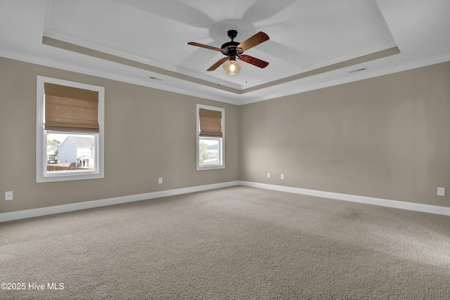carpeted empty room featuring crown molding, a ceiling fan, a raised ceiling, and baseboards