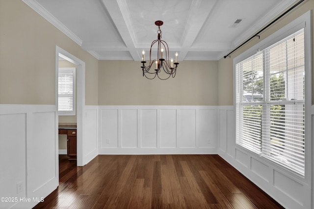 unfurnished dining area with an inviting chandelier, coffered ceiling, a decorative wall, and dark wood finished floors