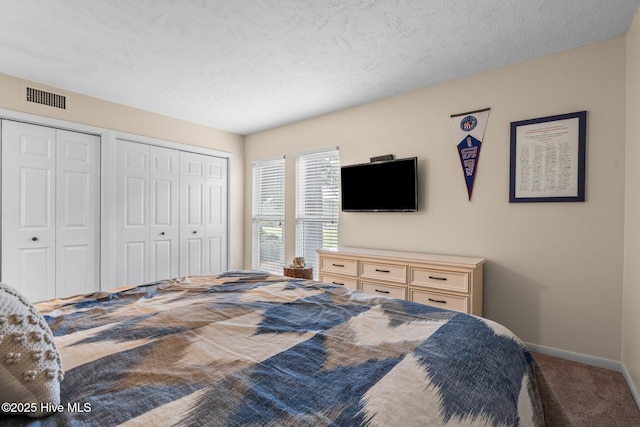 bedroom featuring carpet flooring, baseboards, visible vents, and two closets