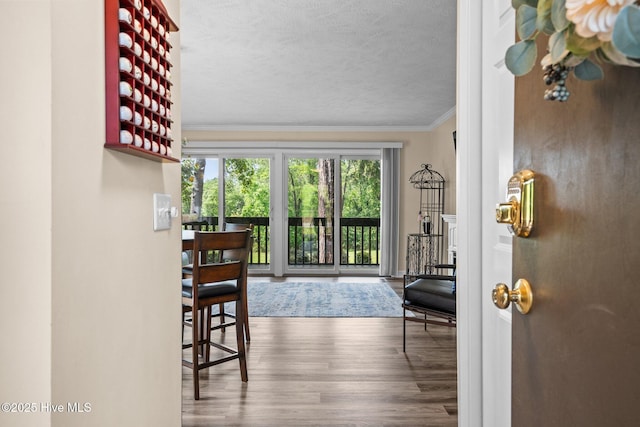 doorway featuring a textured ceiling, ornamental molding, and wood finished floors