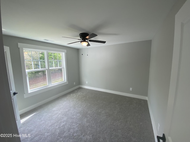unfurnished room featuring baseboards, a ceiling fan, dark carpet, and visible vents