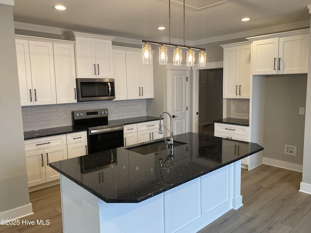 kitchen with appliances with stainless steel finishes, a sink, ornamental molding, recessed lighting, and white cabinetry